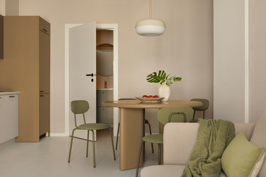 Modern minimal interior design featuring a dining table with green chairs, beige walls, and contemporary lamp in a cozy apartment setting