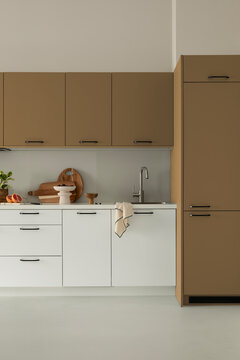 Modern minimalist kitchen interior design with white and brown cabinets, wooden cutting board, sink, and stylish decor for home and architecture concepts