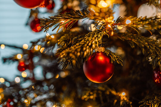 Beautiful vertical video of a shiny purple bauble decorating a green Christmas tree with magical shimmering golden fairy lights in the background.