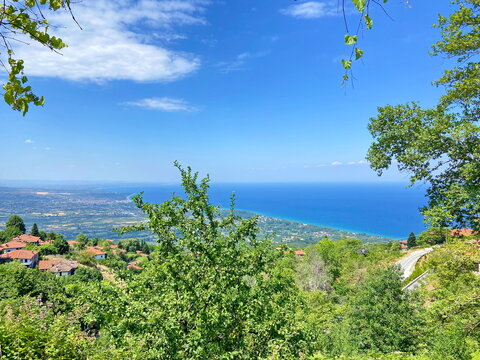 Unsurpassed panorama from the thickets of the mountain forest of the lush blue of the Aegean Sea on the horizon with coastal settlements on the slopes of the mountain hills.