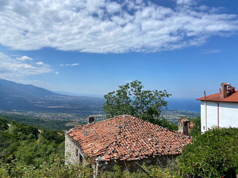 Panorama of mountain ranges in curly clouds descending to the sea coast in the rays of the summer sun.