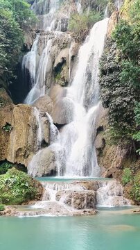 Stunning koe kwang waterfall in kanchanaburi thailand cascading down tiered limestone cliffs into turquoise pool.