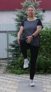 Senior overweight woman exercises outside. Woman doing stretching. Vertical video