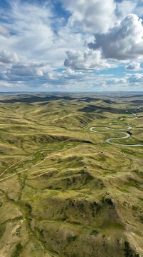 Aerial view of meandering river through rolling green hills