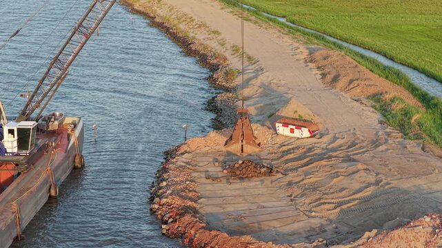 Barge crane removing rocks for dike reinforcement project