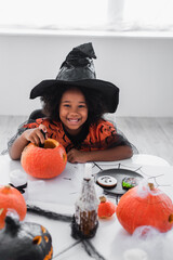 Fototapeta premium Little girl delights in Halloween preparations with pumpkins and treats