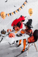 Fototapeta premium Little siblings share joyful moments while creating spooky fun for Halloween