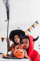 Fototapeta premium Kids enjoying Halloween fun with costumes and pumpkin carving