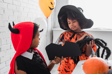 Fototapeta premium Joyful little children dressed in Halloween costumes celebrate the spooky season together