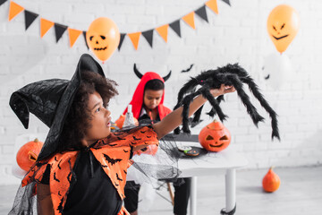 Fototapeta premium Little ones in vibrant Halloween costumes enjoy playful moments together