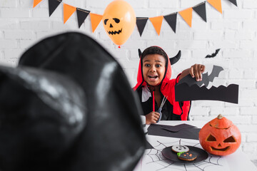 Fototapeta premium Joyful little boy enjoying Halloween crafts with exciting decorations and spooky spirit