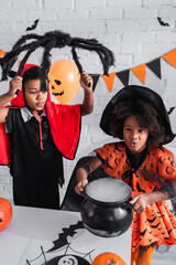 Fototapeta premium Little siblings celebrate Halloween together in vibrant costumes and spooky decorations