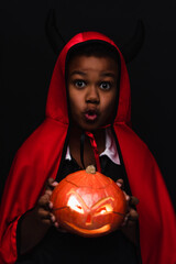 Fototapeta premium Cute little boy in a vibrant Halloween costume holding a glowing jack o lantern