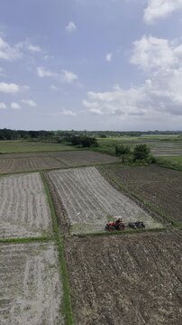 Aerial drone view of Tractor plowing a rice field as egrets feed on freshly turned soil in Southern Palawan