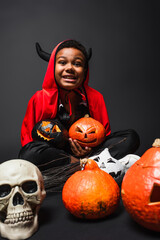 Fototapeta premium Little boy shines in vibrant Halloween costume with spooky decorations around