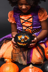 Fototapeta premium Little girl enjoys Halloween with her cheerful orange pumpkin costume