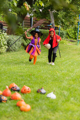 Fototapeta premium Children enjoy Halloween fun in colorful costumes while playing in the yard