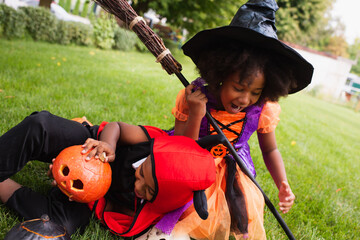 Fototapeta premium Joyful siblings enjoy Halloween costumes and play in a colorful garden on a crisp autumn day