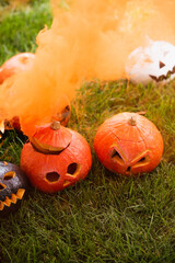 Fototapeta premium Vibrant Halloween pumpkins surrounded by colorful smoke in a festive autumn setting