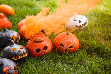 Fototapeta premium Vibrant Halloween pumpkins release smoky orange mist on a grassy lawn