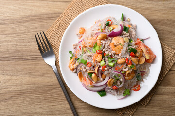 Thai spicy glass noodle salad with minced pork and shrimp (Yum Woon Sen) on a white plate on a wooden background, Table top view © nungning20