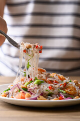 Eating Thai spicy glass noodle salad with minced pork and shrimp (Yum Woon Sen) on a white plate © nungning20