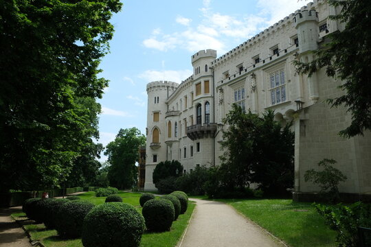 High-quality travel stock photo of famous Hluboka chateau exterior. Scenic neo-gothic architectural detail, towers and manicured garden pathway in Czechia for tourism catalog.
