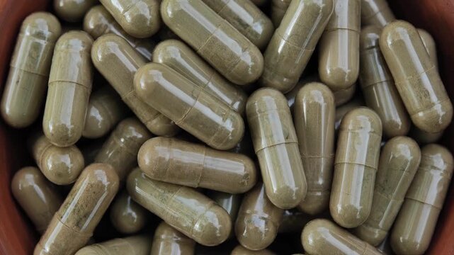 Close-up of capsules containing dried moringa leaf powder, representing herbal supplements, natural plant ingredients, and botanical products. The image highlights the capsules and green moringa mater
