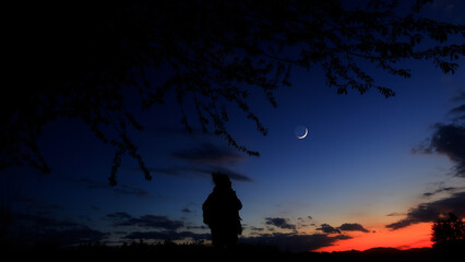 Silhouette of a person in nature observing night sky, Moon, stars and planets from a remote location. © astrosystem
