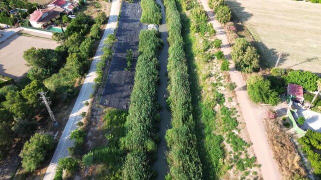 Aerial view of the rio segura surrounded by dense green vegetation and agricultural fields in the rural huerta region of murcia near orihuela during a bright sunny day