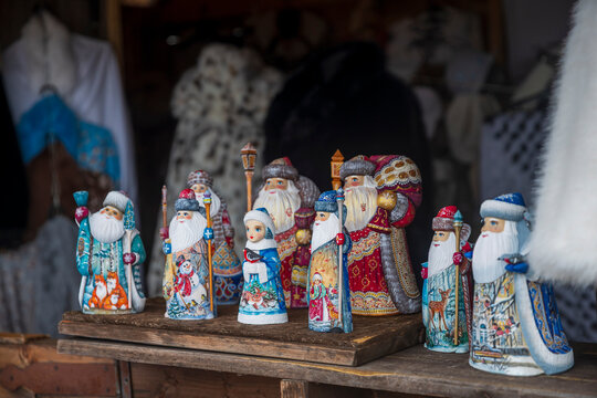 Hand-painted wooden Ded Moroz and Snegurochka figurines displayed on rustic wooden shelf at souvenir stall.