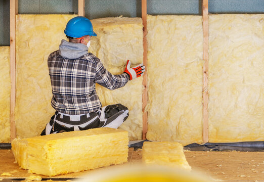 Worker installs insulation in a building during a renovation project