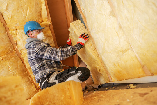Worker installs insulation in a building under construction during the day