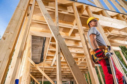 Worker builds wooden structure at construction site in daylight