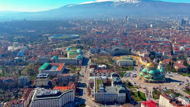 Aerial drone view of Sofia with the Alexander Nevsky Cathedral golden domes, Sofia University, Vasil Levski Stadium and snow capped Vitosha Mountain, Bulgaria, in early spring.