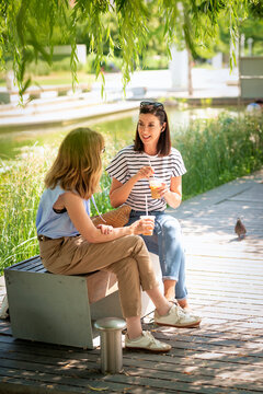 Two mid adult women friends having coffee outdoors