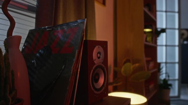 Vinyl record with jazz text resting next to wooden speaker on shelf in room. Footage suitable for marketing campaigns promoting music streaming platforms or home audio equipment