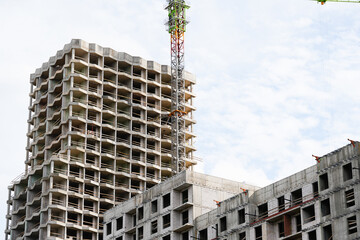 High rise residential building under construction with tower crane and unfinished concrete structure, representing urban development, real estate growth, modern architecture and construction industry © belavinstock