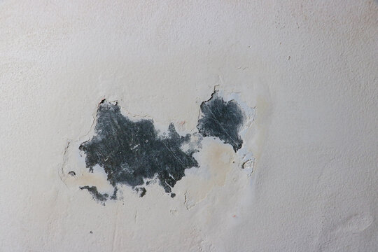 Damaged wall surface showcasing decayed industrial texture with chipped layers of white paint