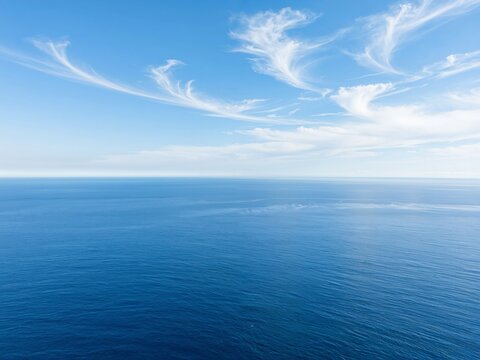 Vast blue ocean under a clear sky with white clouds