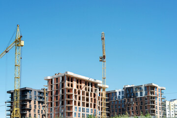 Modern residential buildings under construction with tower cranes and blue sky with white clouds © gorvik