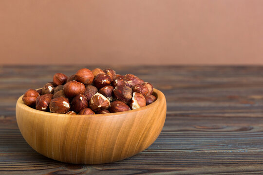 Wooden bowl full of hazelnuts on table background. Healthy eating concept. Super foods
