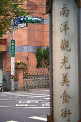 Naklejka premium New Taipei City, Taiwan - Jan 05, 2025: A green Huaxin Street sign hangs from a utility pole, a blurred food street signboard in the foreground, Zhonghe.