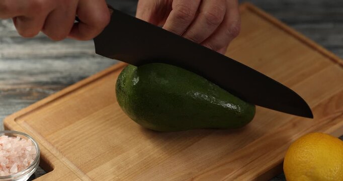 Cook's hand cuts avocado into slices .