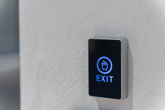 Touch exit button with blue light on the white wall next to the door