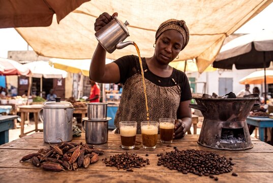 Traditional Preparation of Cafe Touba Coffee by a Senegalese Woman at a Vibrant Outdoor Market