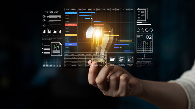 Business Professional Holding Light Bulb with Project Management Dashboard and Data Visualization Elements in Conceptual Workspace. Entropy.