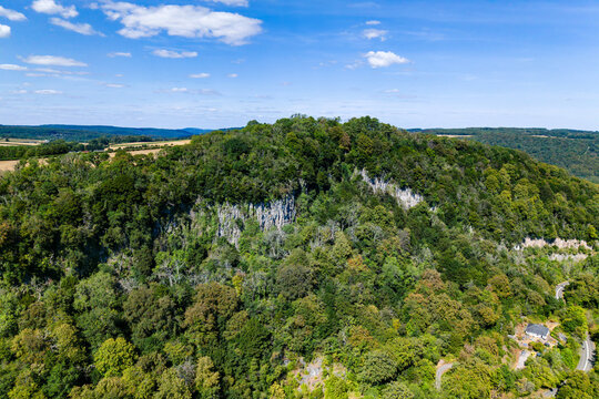 Limestone cliffs rising through dense summer forest at Eagles Nest viewpoint, lush green canopy across the Wye Valley in Monmouthshire, Wales, aerial view