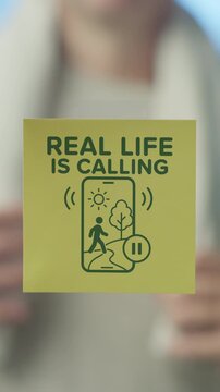 Close up of a person's hands sticking a motivational yellow note on a glass surface, encouraging a digital detox and embracing outdoor activities for better mental and physical well being