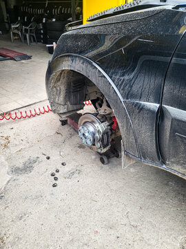 Tire change and installation of new brake rotors on an SUV at an auto repair shop; vehicle jacked up with one wheel removed during auto repair and maintenance work on the brake system to ensure road s